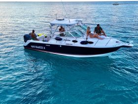 A couple enjoys a relaxing moment on the bow of the Main Squeeze II, surrounded by crystal-clear waters — perfect for sunbathing and soaking up the sun.