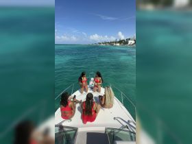 A lively group of friends enjoys a sunny day on the boat, celebrating with drinks and laughter against a stunning turquoise backdrop — perfect for unforgettable summer outings.