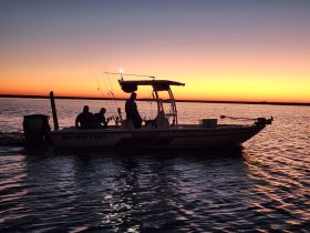A group of anglers enjoys a fishing trip at sunset aboard a Skeeter boat, creating a picturesque scene on the water.