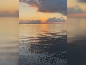 A serene sunset over calm waters, reflecting vibrant colors — perfect for capturing the tranquility of evening boat rides.