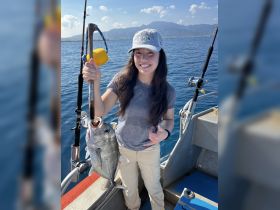 A woman proudly displays her catch while fishing on a boat, showcasing the excitement of a successful day on the water.