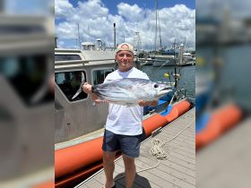 A proud angler displays his impressive catch at the marina, showcasing the thrill of fishing adventures on the water.