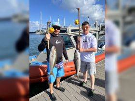 Two anglers proudly display their catch after a successful fishing trip, showcasing the thrill of fishing adventures on the water.
