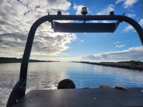 A serene view from a boat, capturing the tranquil waters and dramatic cloud formations, perfect for showcasing the beauty of a day on the water.