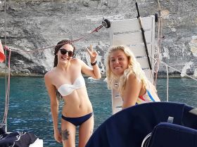 Two friends pose joyfully on a boat, enjoying a sunny day by the water — perfect for summer adventures and memorable moments.