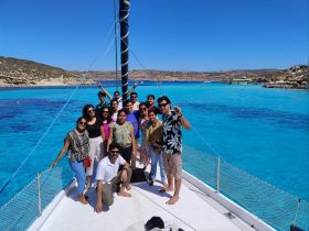 A lively group poses on the deck of a boat against a stunning backdrop of turquoise waters, capturing the joy of their boating adventure.