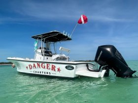 A striking view of the 'Danger Charters' speedboat anchored in clear turquoise waters, showcasing its sleek design and vibrant branding.