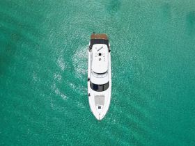 A stunning aerial view of a luxurious yacht gliding over crystal-clear turquoise waters, perfect for showcasing high-end boating experiences.