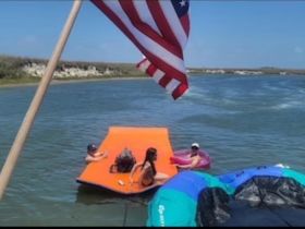 A lively group enjoys a sunny day on the water, relaxing on a floating mat and soaking up the summer vibes.