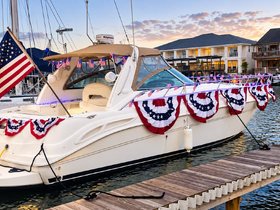 A beautifully decorated yacht adorned with patriotic bunting and an American flag, docked at sunset — perfect for festive celebrations on the water.