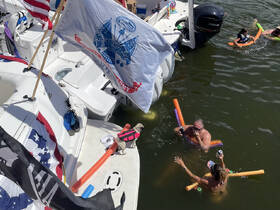 A lively group enjoys a fun day in the water with pool noodles, drinks, and a dog on board — perfect for summer parties and family outings.