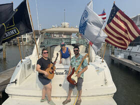 A lively group of friends enjoys a musical moment aboard their boat, showcasing a fun and festive atmosphere perfect for gatherings on the water.
