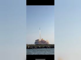A rocket launch is captured against a clear sky, with smoke billowing from the launch site. The image showcases a unique moment but lacks clarity regarding the boating context.