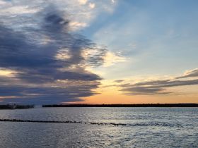 A scenic view of the sky and water at sunset, showcasing beautiful cloud formations and tranquil waters.