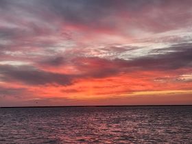 A stunning sunset paints the sky in vibrant hues over the tranquil waters, creating a picturesque backdrop for evening boat trips.