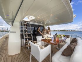 A lively group enjoys cocktails and a meal on the deck of a luxurious yacht, perfect for celebrations and social gatherings on the water.