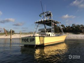 A beautiful view of the 'TIDE UP' boat docked at Panama City Beach, showcasing its sleek design against a serene backdrop of sandy shores and blue skies.