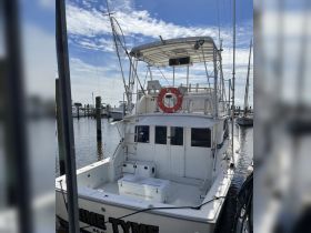 A clear view of the back of the 'Prime Tyme' charter boat docked at the marina, showcasing its spacious design and amenities.