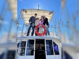 A cheerful family poses together on the deck of a boat, capturing a memorable moment under the clear blue sky — perfect for family outings and celebrations on the water.