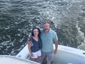 A happy couple poses together on the deck of their boat, enjoying a memorable moment on the water — perfect for romantic getaways or celebrations.