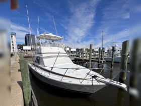 A sleek yacht docked at the marina, showcasing its elegant design against a backdrop of blue skies and nearby boats.