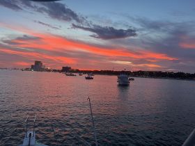 A stunning sunset view over the water with boats anchored, showcasing the serene beauty of evening on the water.