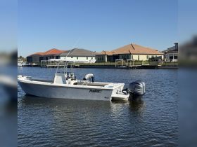 A sleek speedboat is docked in calm waters, showcasing its modern design against a backdrop of waterfront homes.