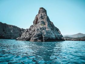 A stunning view of a rocky coastline rising from the turquoise waters, showcasing the natural beauty of the area — perfect for scenic boat tours and exploration.