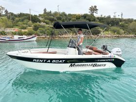 A man operates a rental boat in serene waters, showcasing the perfect opportunity for boating and fishing adventures. Contact details for Mirabello Boats are visible for easy booking.