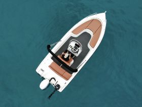 Aerial view of a sleek speedboat cruising through clear waters, showcasing its stylish design and comfortable seating.