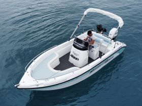 A sleek speedboat captured from above, showcasing its design and features while a person is seated at the helm, ready for an adventure on the water.