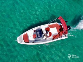 Aerial view of a boat cruising through crystal-clear waters, showcasing the vibrant red seating and the excitement of a day on the water.