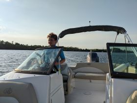 A young boy sits at the helm of a boat, ready for an adventure on the water — perfect for family outings and learning to navigate.