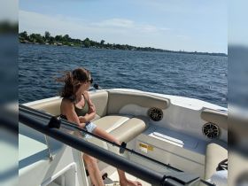 A woman enjoys a sunny day on a boat, taking in the scenic views of the water and shoreline — a perfect moment for relaxation on the water.