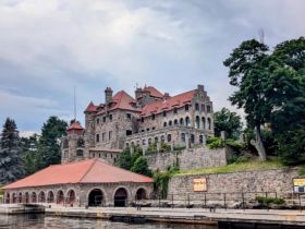 A scenic view of a historic stone castle by the water, surrounded by lush greenery, ideal for exploring architectural beauty and waterfront landscapes.