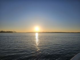 A serene sunset view over calm waters, showcasing the beautiful reflection of the sun — perfect for tranquil evening boat rides.