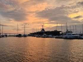 A picturesque sunset view over a marina filled with various yachts, showcasing the tranquil beauty of boating life.