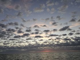 A serene view of a cloudy sky over the ocean at sunset, capturing the tranquil beauty of nature.