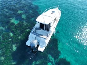 Aerial view of a sleek boat cruising over crystal-clear waters, showcasing the vibrant underwater scenery below — perfect for exploring coastal destinations.