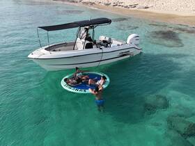A group of friends enjoys a relaxing day on a floating mat in crystal-clear waters, with a boat anchored nearby — perfect for summer fun and beach outings.
