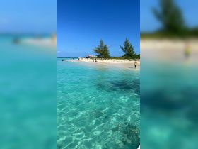 A vibrant beach scene with people enjoying the clear turquoise waters and sandy shores, perfect for a day of relaxation and fun in the sun.