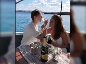 A couple enjoys a romantic moment aboard a yacht, toasting with drinks against a stunning ocean backdrop — perfect for special celebrations or intimate getaways.