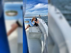 A young girl enjoys a boat ride with her dog, gazing out at the water — a perfect moment of companionship on the water.