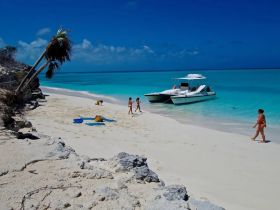 A vibrant beach scene featuring a group enjoying the sun and sand, with a boat anchored nearby — perfect for a relaxing day on the water.
