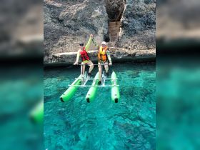 Two friends enjoy a fun paddleboarding experience in crystal-clear waters, showcasing the joy of water activities and adventure.