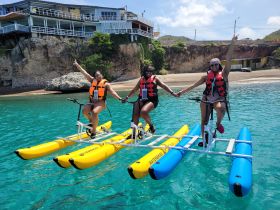 Three friends enjoy a fun-filled day on waterbikes, showcasing their excitement against a beautiful coastal backdrop — perfect for adventurous outings.