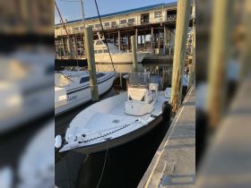 A sleek center console boat docked at the marina, showcasing its clean lines and modern design, perfect for fishing or leisurely outings.