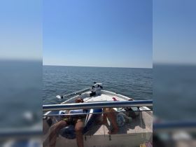 Guests relax on the deck of a boat under the bright sun, enjoying a peaceful day on the water.