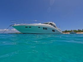 A stunning view of a sleek yacht anchored in crystal-clear waters, showcasing its elegant design against a vibrant blue backdrop.
