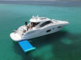 A lively group enjoys time aboard the 'Lucky Penny' yacht, showcasing the perfect setting for fun on the water with stunning turquoise surroundings.